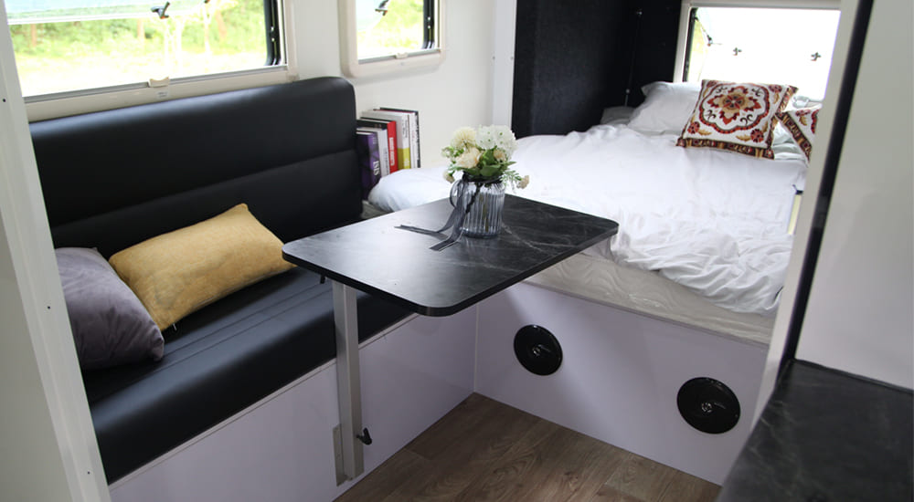 Fixed bed and convertible dinette layout options inside a compact Ecocampor caravan